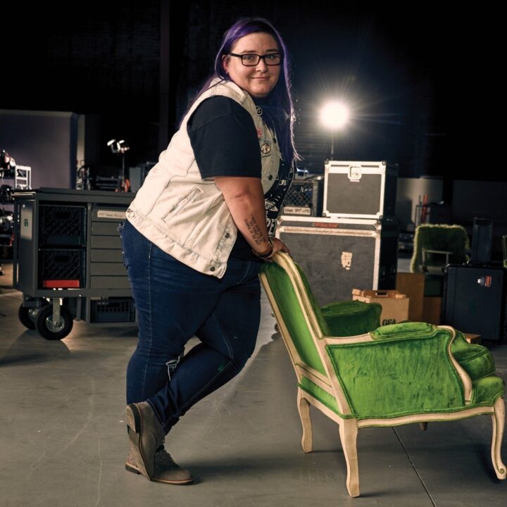 Full-body picture of Catrina Dygert leaning on a green armchair.
